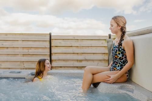 two girls sitting in a hot tub at Sauna Moments Villa in Torhout