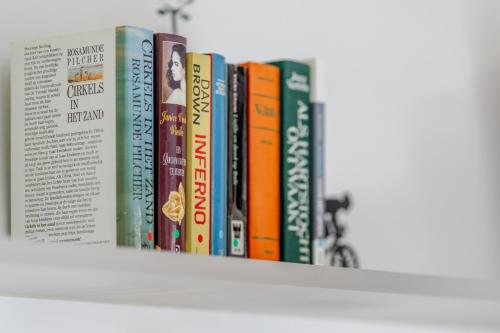 a row of books sitting on a shelf at Sauna Moments Villa in Torhout