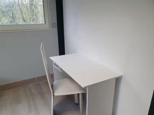 a white desk with a chair next to a window at la tanière argentée in Nailloux