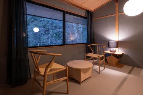 a room with two chairs and a table and a window at くらま温泉 in Kyoto