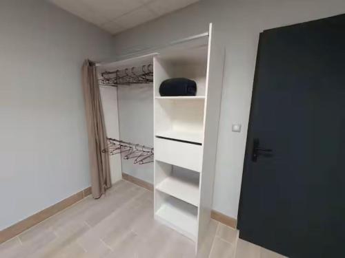 a walk in closet with white shelves and a door at la tanière argentée in Nailloux
