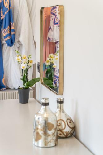 a mirror on a shelf with two glass bottles and a vase at PERATZADA central suite in Argostoli
