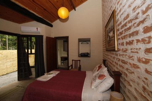 a bedroom with a bed and a brick wall at Apoena Chales da Ilha in São Francisco Xavier