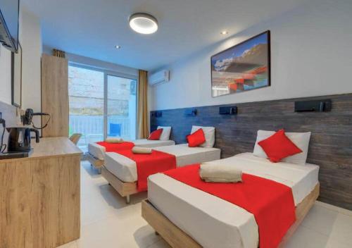 a bedroom with three beds with red and white sheets at Bayside A Apartments in St Julian's