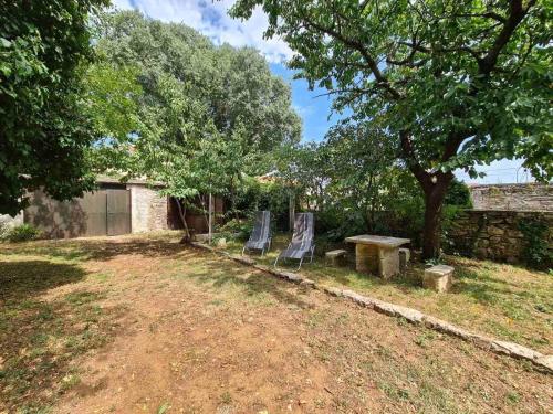 2 chaises, une table et un arbre dans la cour dans l'établissement Ferienhaus für 6 Personen ca 90 qm in Krnica, Istrien Bucht von Raša, à Krnica