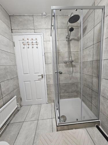 a shower with a glass door in a bathroom at Three bedroom house with a park in Dagenham