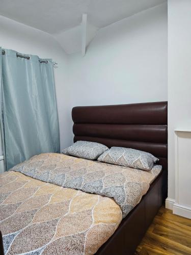 a bed with a brown headboard in a bedroom at Three bedroom house with a park in Dagenham