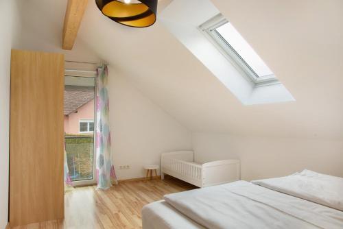 a white bedroom with a bed and a window at Christines Ferienwohnung in Eitting