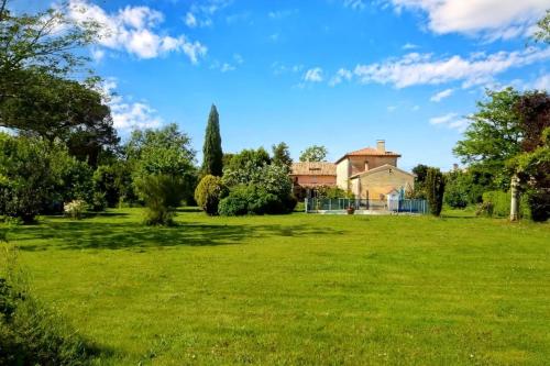 un grande campo verde con una casa sullo sfondo di Cinégîte du jardin aux étoiles - Proche de Saint Emilion a Saint-Pey-de-Castets