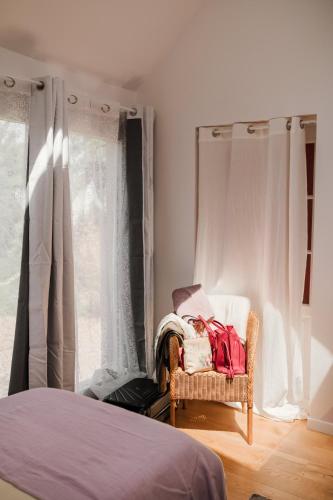 a bedroom with a bed and a chair and a window at La Maison Gioia in Nerville-la-Forêt