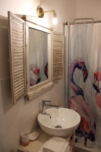 a bathroom with a sink and a shower with a flamingo shower curtain at Art b&b Gli Aironi in Pomposa
