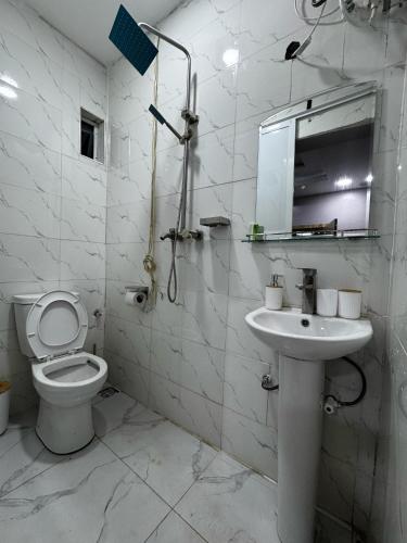 a white bathroom with a toilet and a sink at Prime OAK Residence in Lagos