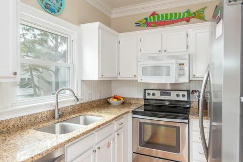 a kitchen with white cabinets and a sink and a microwave at Shipwatch Beach House - Ocean Views! Shared Pool! in Cedar Reef Villas