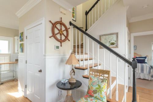 a room with a staircase with a table and a chair at Shipwatch Beach House - Ocean Views! Shared Pool! in Cedar Reef Villas