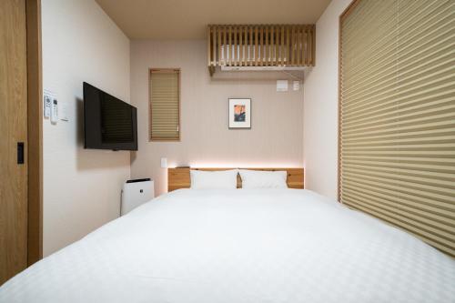 a bedroom with a large white bed and a flat screen tv at YADO TENKU Kyoto Nijo in Kyoto