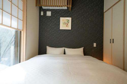 a bedroom with a large white bed and a window at YADO TENKU Kyoto Nijo in Kyoto