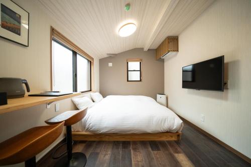 a bedroom with a bed and a desk and a tv at YADO TENKU Kyoto Nijo in Kyoto