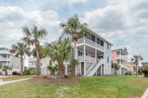 a large house with palm trees in front of it at Shipwatch Beach House - Ocean Views! Shared Pool! in Cedar Reef Villas