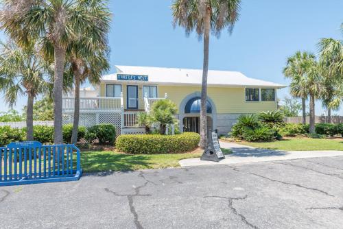 a yellow house with palm trees in front of it at Shipwatch Beach House - Ocean Views! Shared Pool! in Cedar Reef Villas