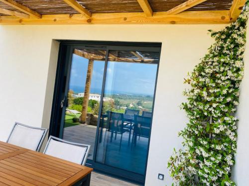 une terrasse avec une table, des chaises et une plante dans l'établissement Magnifique appartement vue mer et montagne à Solenzara Corse, à Sari-Solenzara