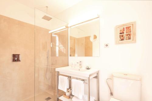 a bathroom with a sink and a shower and a toilet at Hotel y Apartamentos DES PUIG in Deia