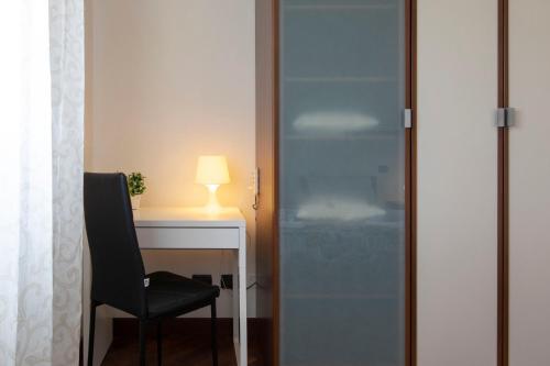 a glass door next to a desk with a chair at Alloggio turistico Suite Leonardo - Rome, 20m in treno -Fiumicino Airport, 2m in treno- Fiera, 2m in treno in Fiumicino