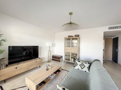 un salon avec un canapé et une grande télévision à écran plat dans l'établissement Appartement dans résidence avec piscine, à Calvi