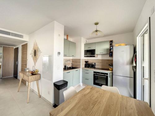 une cuisine avec une table et un réfrigérateur blanc dans l'établissement Appartement dans résidence avec piscine, à Calvi