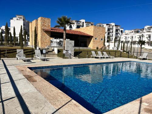 a swimming pool with chairs and a building at Viñedos de San Antonio Condominium in Ensenada