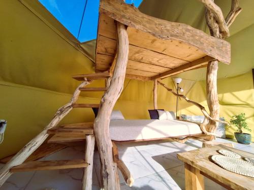 a tree house bedroom with a bed made out of logs at Miško Pašvaistėje - poilsis gamtoje in Balneliškiai