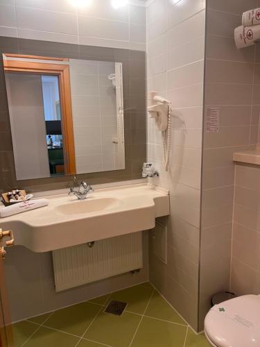 a bathroom with a sink and a mirror and a toilet at Hotel Jasmine in Braşov