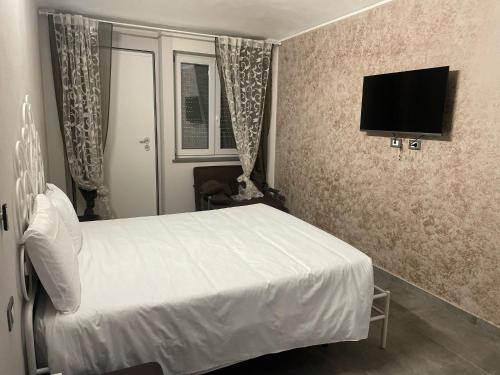 a bedroom with a white bed and a flat screen tv at airport apartments camera narciso in San Maurizio Canavese