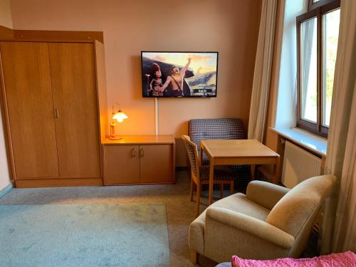 a living room with a table and a tv on the wall at Hotel Quickborner Hof in Quickborn