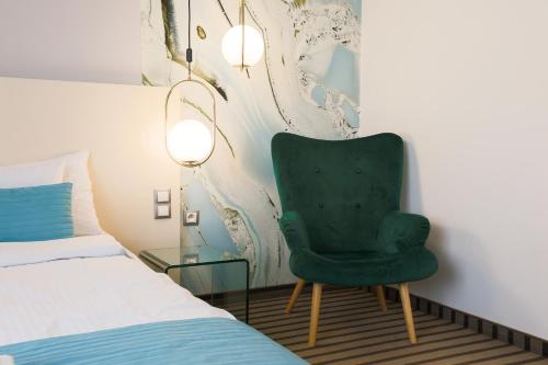a bedroom with a green chair and a glass table at NoBo Hotel - business in Łódź