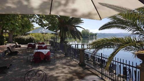 a patio with tables and chairs next to a body of water at Hotel Eden Sul Lago in Bolsena