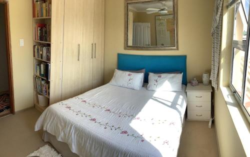 a bedroom with a bed with a blue headboard and a mirror at Scherers Ecke in Hentiesbaai