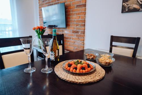 a table with a bowl of fruit and a bottle of wine at Apartamentowiec Panorama Gór City Center Family&Pet-friendly in Szklarska Poręba