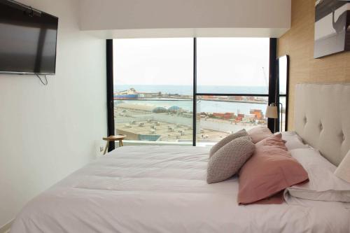 a bedroom with a bed with a view of a beach at HOM I Acogedor y Cómodo depto de 1Dorm Vista al Mar PNM 0114 in Antofagasta