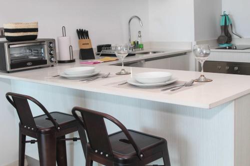 a kitchen with two chairs and a counter with plates and wine glasses at HOM I Acogedor y Cómodo depto de 1Dorm Vista al Mar PNM 0114 in Antofagasta