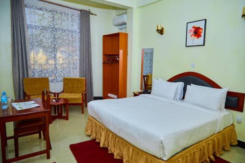 a hotel room with a bed and a table and a bed at KiliCrane Lodge Arusha in Arusha
