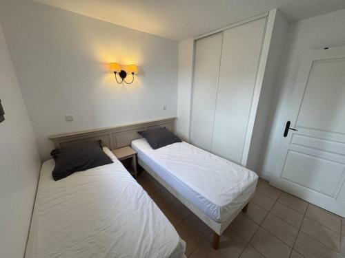 - 2 lits dans une petite chambre avec une lumière sur le mur dans l'établissement T3 rénové avec piscine et parking au Cap d'Agde - FR-1-749-79, au Cap d'Agde