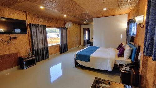 a bedroom with a bed and a flat screen tv at Whispering Woods Resort in Lonavala