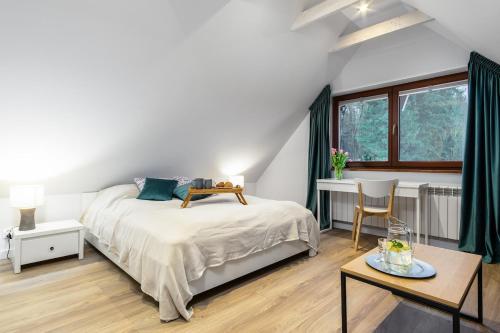 a white bedroom with a bed and a table at Siedlisko przy Młynie in Cisze