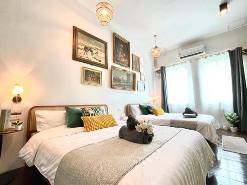 two beds in a room with paintings on the wall at Entire house,Unwind in the city, near GrandPalace in Bangkok