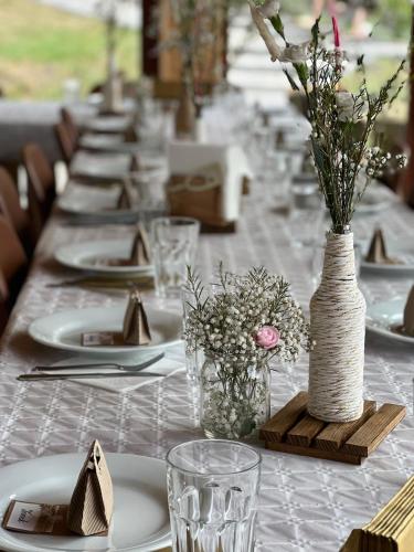 a long table with white plates and vases with flowers at Siedlisko przy Młynie in Cisze