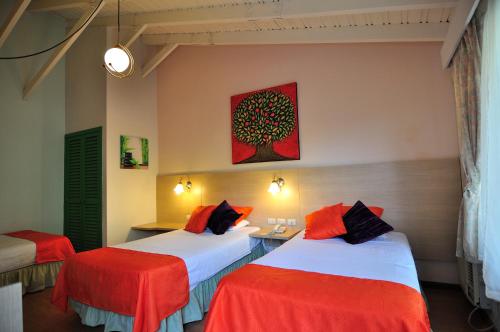 Habitación con 2 camas y sábanas rojas y blancas. en Hosteria Canoa en Canoa