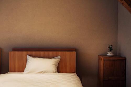 a bed with a wooden headboard and a white pillow at 森長旅館 Moricho Ryokan in Oga