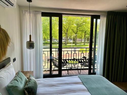 a bedroom with a bed and a balcony with a table at Hotel La Boutique in Nijmegen