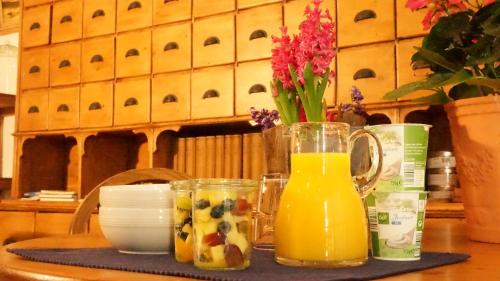 een tafel met twee glazen sinaasappelsap en een vaas met bloemen bij Gästehaus Kersting in Meerbusch