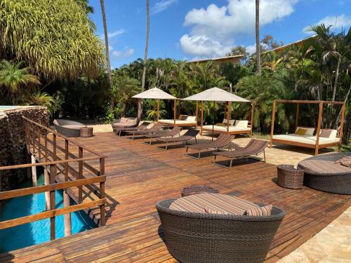 a deck with chairs and umbrellas next to a pool at Pousada dos Girassóis in Pipa